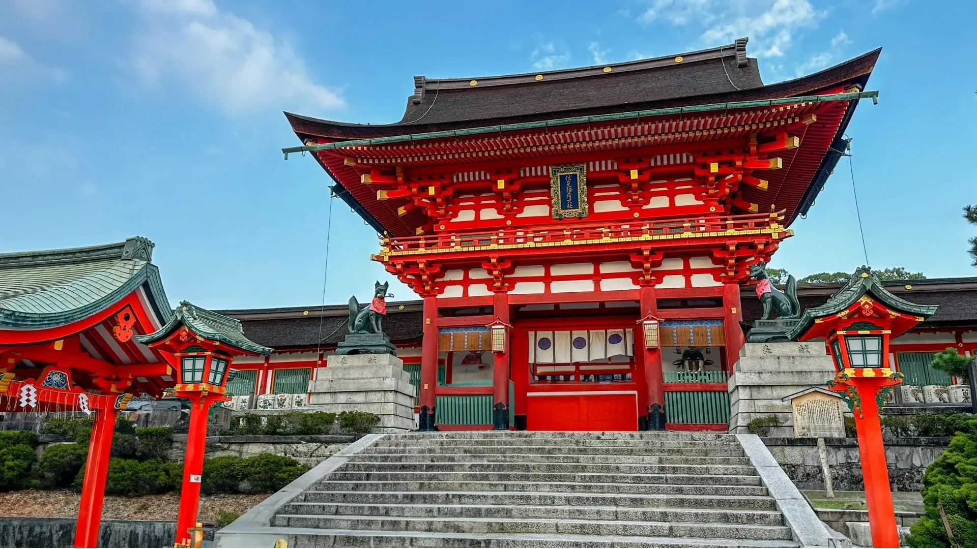 Kırmızı ve beyaz renkleri, geleneksel çatı detayları, taş basamakları ve tilki heykelleriyle dikkat çeken Japon Şinto tapınağı.