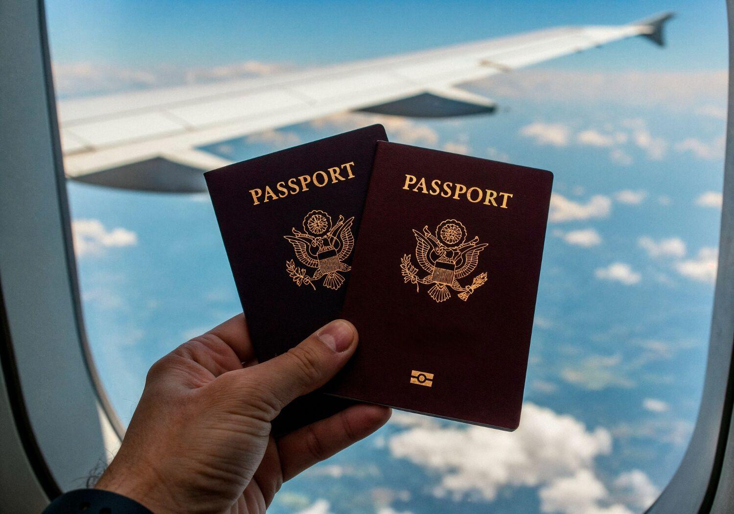 Uçak penceresinin önünde iki pasaport tutan bir yolcunun eli